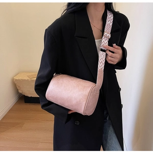 Pink minimalist pillow shoulder bag with embroidered strap shown on model outdoors