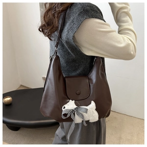 Dunkelbraune Hobo-Tasche aus Leder mit Plüschwelpen-Deko, präsentiert an einem Model