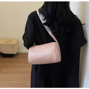 Side view of mauve cylindrical shoulder bag with a wide geometric jacquard strap