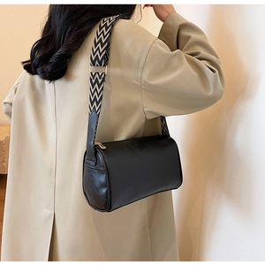 Detail of black cylinder bag with black and white geometric patterned wide shoulder strap
