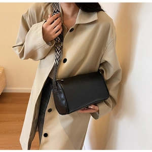 Detail view of a black cylinder bag featuring a black and white geometric wide strap