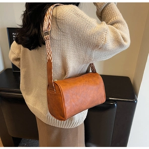 Brown cylinder shoulder bag with vintage leather texture and geometric patterned strap