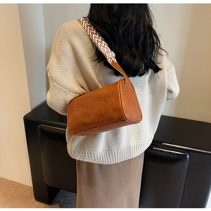 Chic brown leather pillow bag with retro geometric patterned shoulder strap shown on model