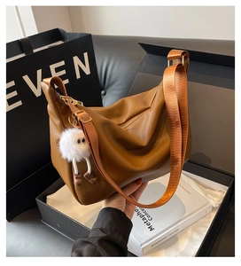 Brown lychee leather hobo bag with wide nylon strap and plush charm detail