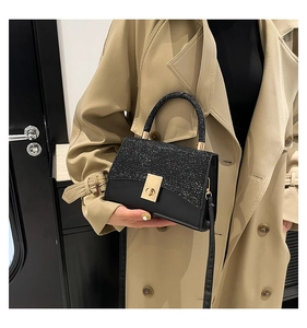 Dettaglio borsa nera con paillettes e chiusura dorata indossata con un trench beige