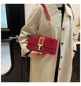Detail of red crocodile texture crossbody bag with gold chain and black-gold lock