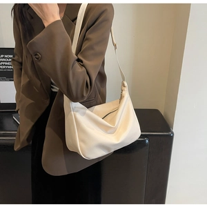 Detail of creamy white crescent shoulder bag with lychee texture and adjustable strap