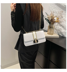 Detailed view of white crocodile pattern crossbody bag with golden chain and clasp