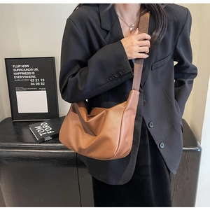 Detail of caramel brown pebble leather hobo bag with wide shoulder strap on a model