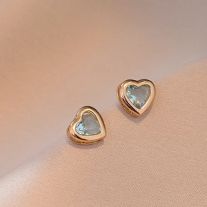 Boucles d'oreilles cœur en or rose avec zircons bleu clair sur tissu de soie