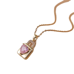 Collier cadenas doré avec pierre précieuse cœur rose et cristaux sur fond blanc épuré