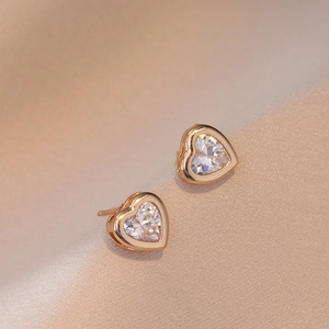 Boucles d'oreilles cœur en or rose élégantes avec zircon sur fond de soie douce