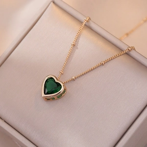 Elegant gold chain necklace featuring a heart-shaped emerald green zircon pendant on velvet