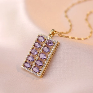 Macro detail of a gold necklace featuring purple stones and pavé set cubic zirconia