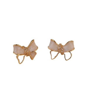 Elegant bow-shaped stud earrings in cream white and gold with sparkling rhinestones