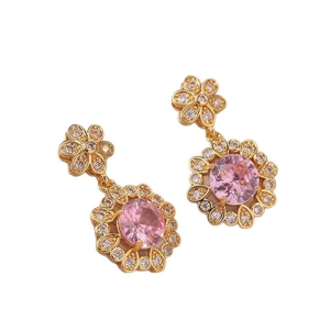 Boucles d'oreilles fleurs dorées avec pierre rose et cristaux de zircon sur fond blanc