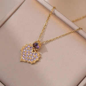 Collier élégant avec pendentif cœur doré et zircons violets dans un coffret à bijoux beige