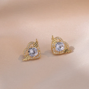 Elegante goldene Herz-Engelsflügel-Ohrringe mit Zirkonia auf champagnerfarbenem Satin
