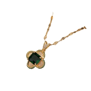 Gold clover necklace with emerald zircon pendant on white background