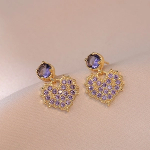 Elegant gold heart earrings with purple rhinestones and crystal studs on pink fabric