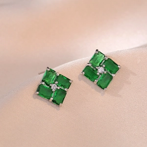 Elegant emerald green zircon geometric stud earrings on soft beige silk background