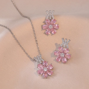 Schmuckset mit rosa Zirkon-Blumenhalskette und Ohrringen auf Seidenhintergrund