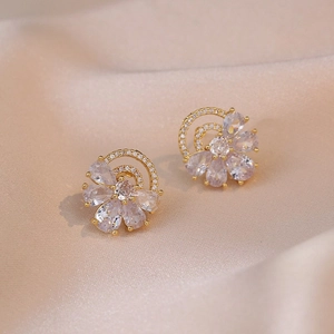 Elegant floral stud earrings with sparkling cubic zirconia on champagne silk background