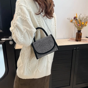 Sac à main élégant en strass avec bandoulière chaîne porté par un mannequin chez soi