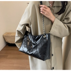 Close-up of black quilted leather tote bag with elegant gold chain strap detail