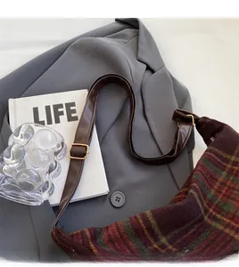 Detail of adjustable leather strap and golden buckle on a vintage plaid shoulder bag