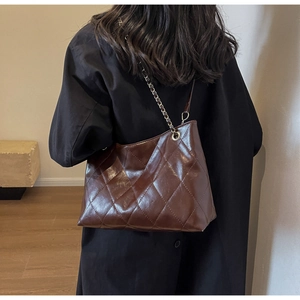 Detail of dark brown quilted leather tote with elegant gold-tone metal chain strap