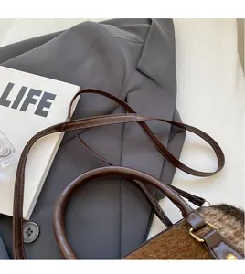 Detail of dark brown wool crossbody bag featuring round handle and smooth shoulder strap