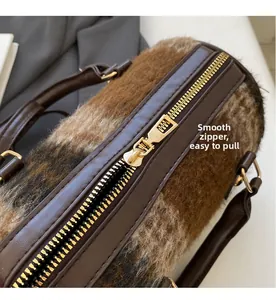 Close-up of smooth gold zipper and soft brown plush texture on cylindrical handbag