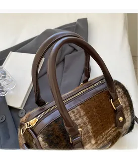 Detail of plush faux fur shoulder bag with brown leather handles and golden zippers