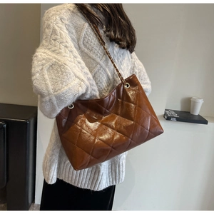 Close-up of caramel tote bag featuring quilted stitching and glossy wax leather finish