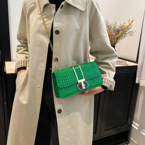 Green crocodile pattern crossbody bag with gold chain strap shown on beige trench coat