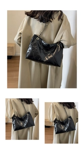 Detailed close-up of a black quilted tote bag featuring a leather-woven chain shoulder strap