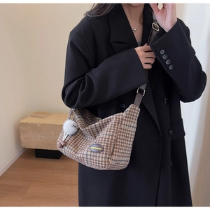 Détail du sac à bandoulière vintage en laine marron à carreaux avec pompon et étiquette cuir