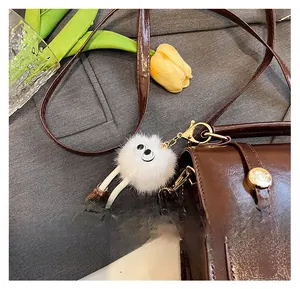 Gros plan d'un pendentif monstre en peluche blanche sur un sac à main en cuir marron