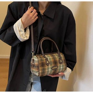 Gros plan d'un sac cylindrique vintage à carreaux avec lanières en cuir sur modèle