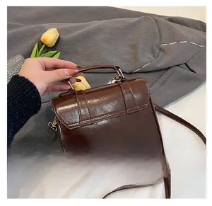Détail de l'arrière du sac bandoulière vintage en cuir PU marron brillant avec dorures