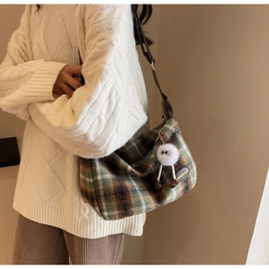 Detail view of plaid fabric shoulder bag with funny plush charm and adjustable strap