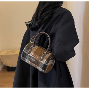 Detail view of brown checkered plush cylinder bag with leather straps and gold metal hardware