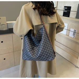 Detail of grey patterned tote bag with brown straps worn over the shoulder by a model