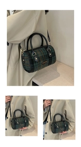 Detail of green plaid wool boston bag showing leather logo and adjustable shoulder strap