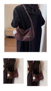 Détail d'un sac à carreaux rouge et vert avec breloque peluche et bandoulière en cuir