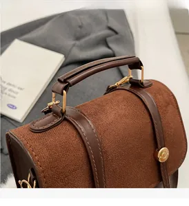 Detail of the brown frosted suede bag showing the durable handle and metallic hardware