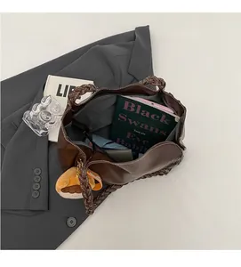 Detail of a brown tote bag featuring woven handles and spacious interior with plush charm
