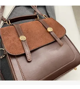 Close-up of brown vintage backpack featuring faux leather and suede texture with gold buckles