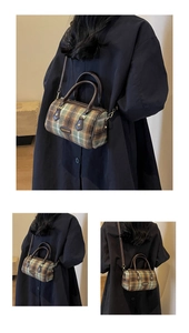 Detail of vintage plaid cylinder bag showing green and brown wool fabric and handles